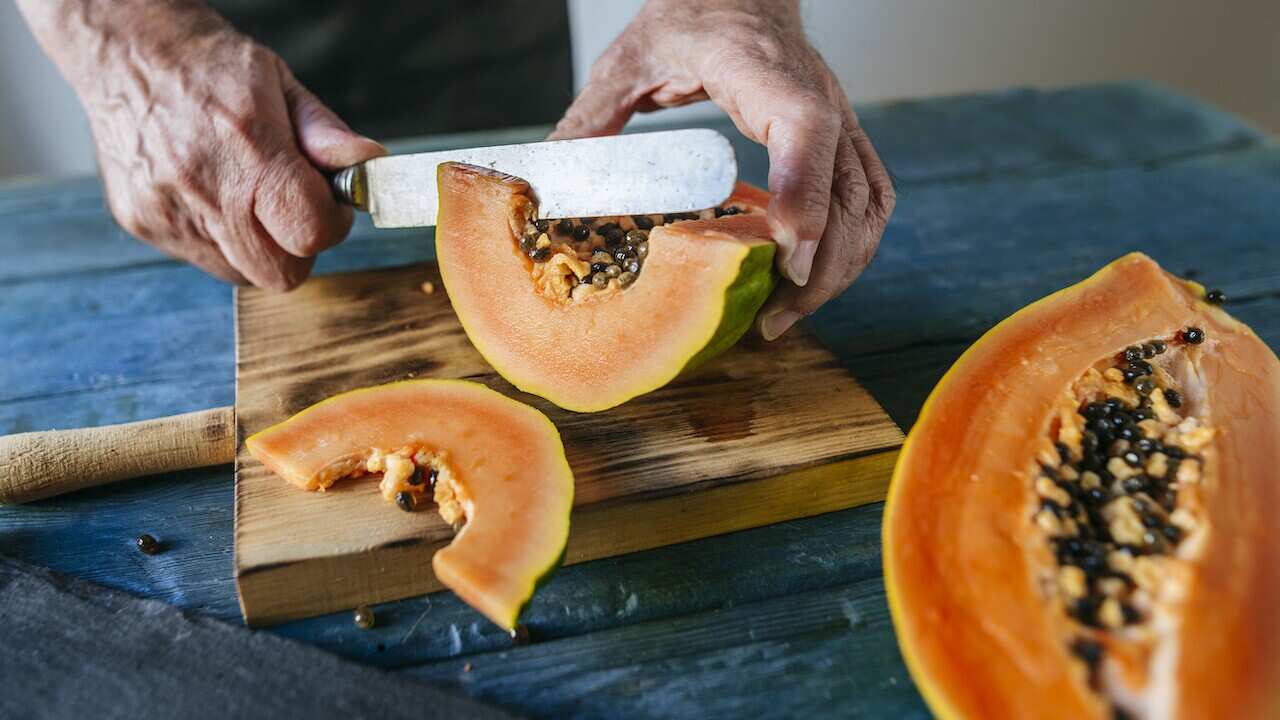 Hands of senior man cutting papaya