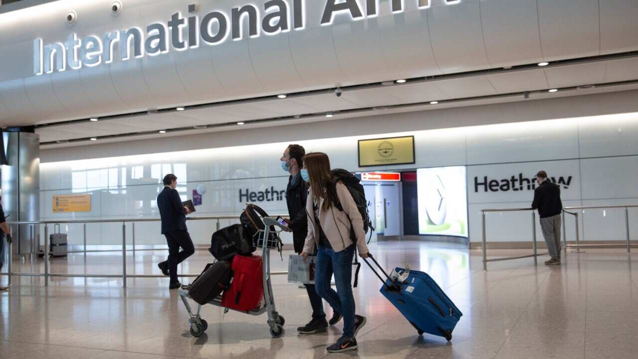 In this file photo dated Monday, June 8, 2020, passengers wearing face masks arrive at London's Heathrow Airport. The two-week quarantine period that travelers arriving in England from a destination not on the British government’s coronavirus safe list co