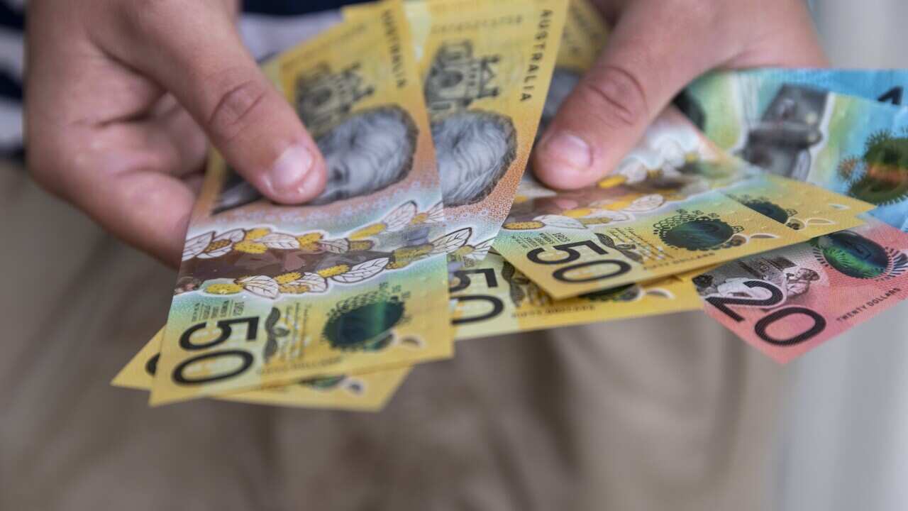 Male person holding some Australian currency