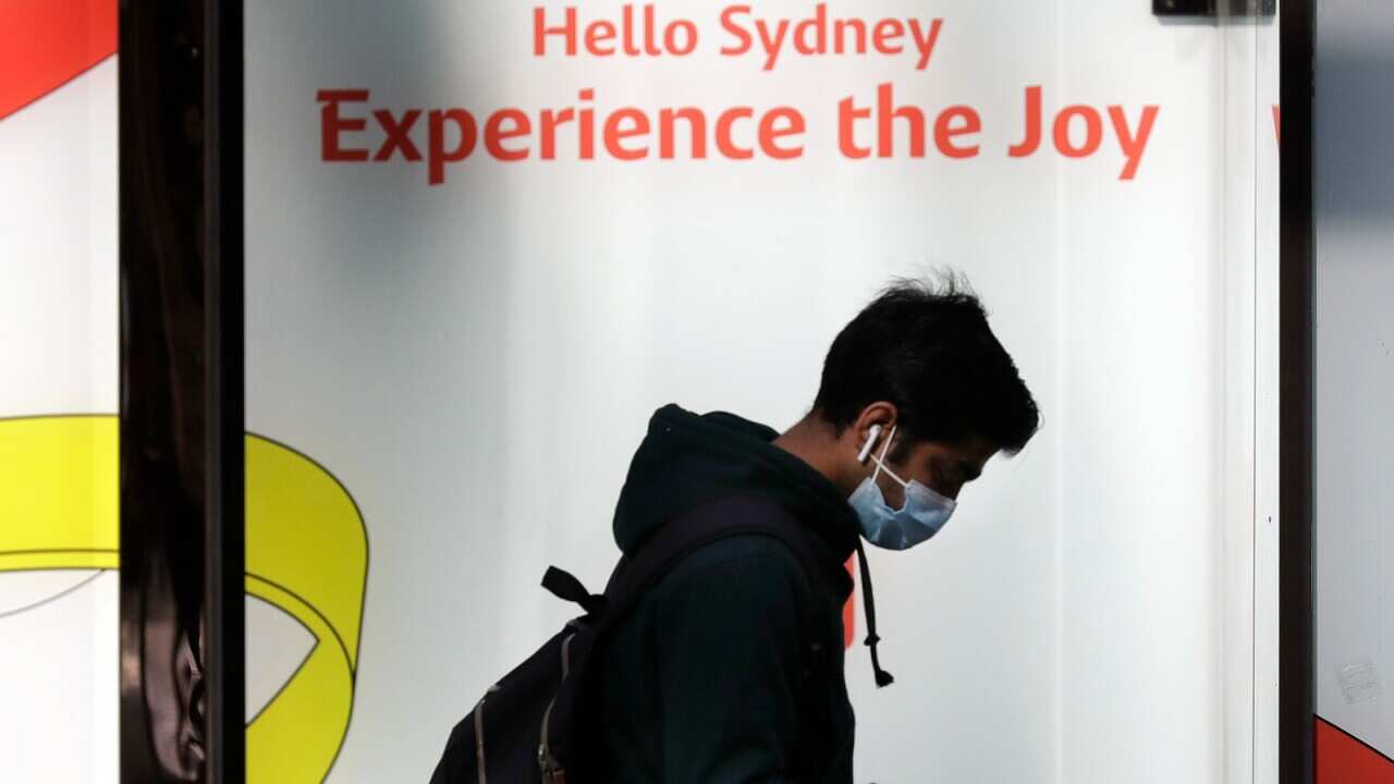A man wears a mask as he walks in Sydney, Wednesday, July 7, 2021. Sydney's two-week lockdown has been extended for another week due to the vulnerability of an Australia population largely unvaccinated against COVID-19, officials said.