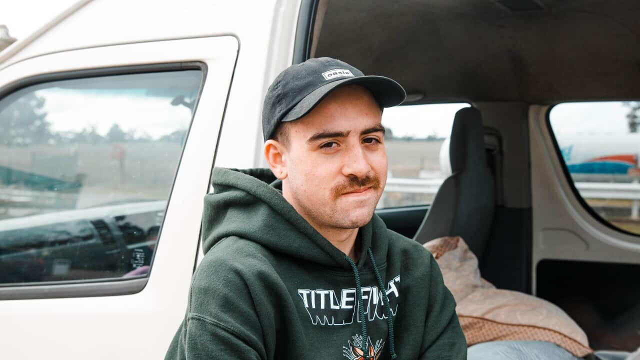 Young man standing beside van.