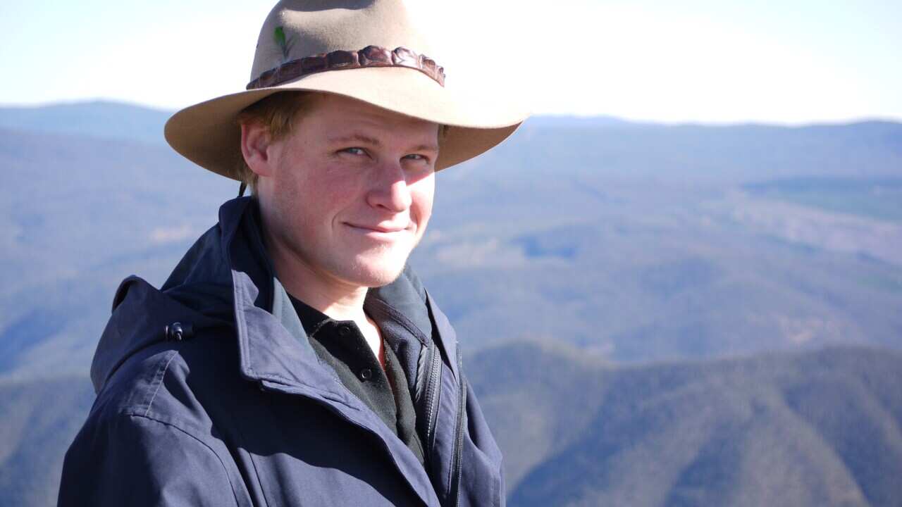 A man smiling with mountains in the background.