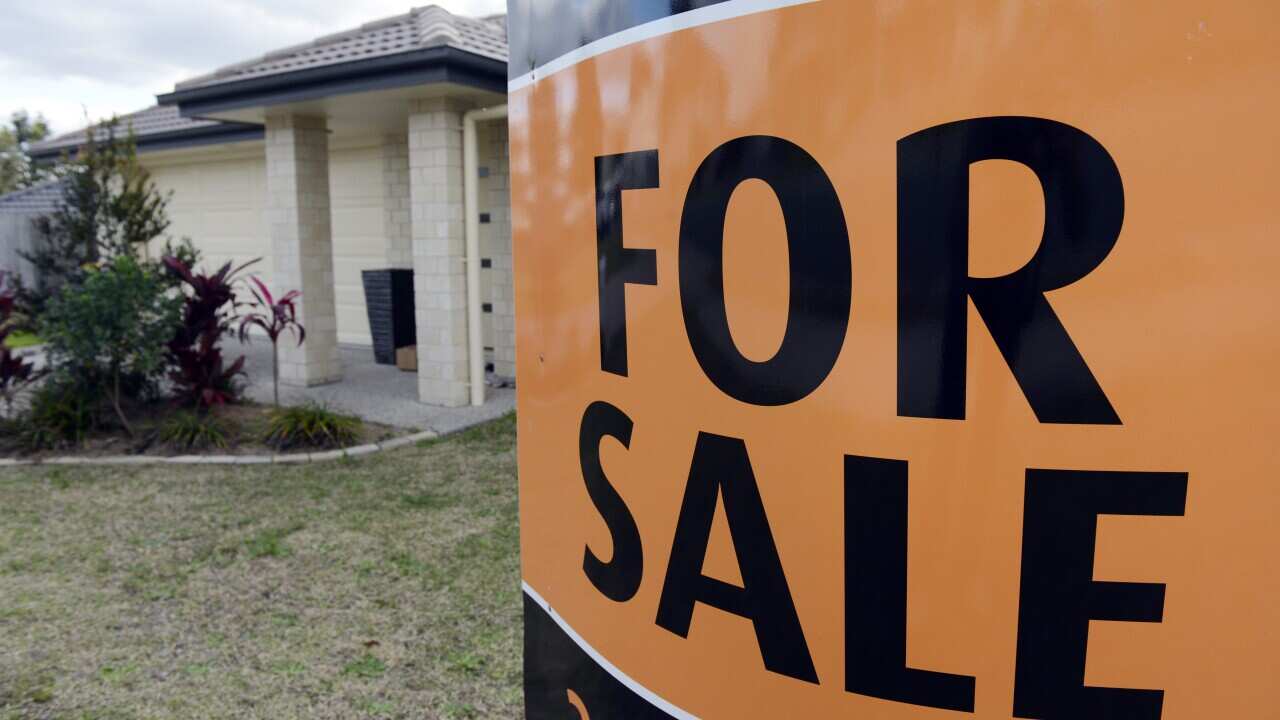 An orange "For Sale" sign is seen in front a stereotypical suburban house. 