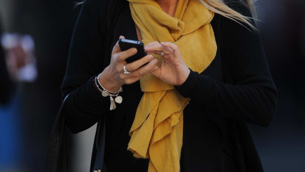 A woman looks at her mobile phone