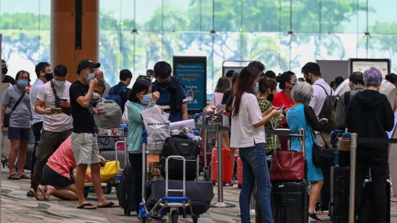 Passengers queue to check-in for their flights prior to departure