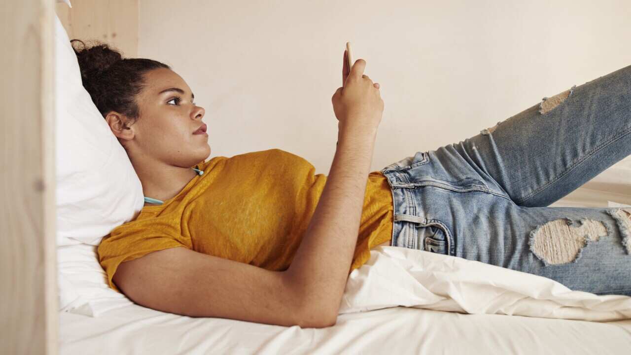 Young woman checking phone in bunk bed