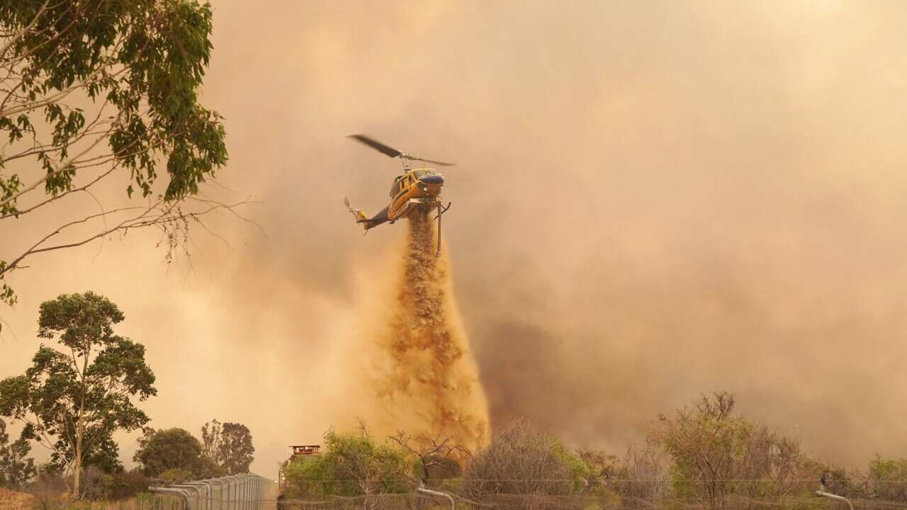 A helicopter drops fire retardant on a fire near Wooroloo
