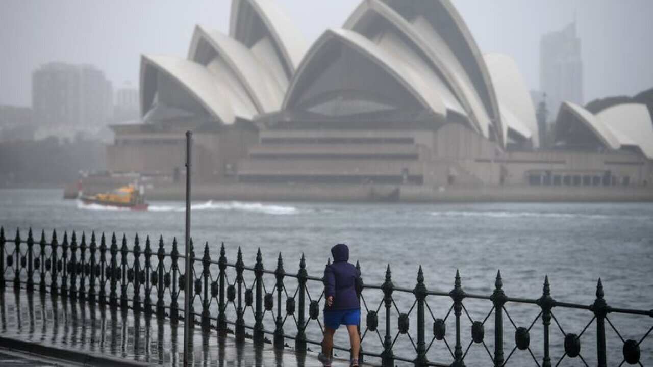 A person is seen walking as rain continues to fall in Sydney, Friday, October 5, 2018. (AAP Image/Dan Himbrechts) NO ARCHIVING