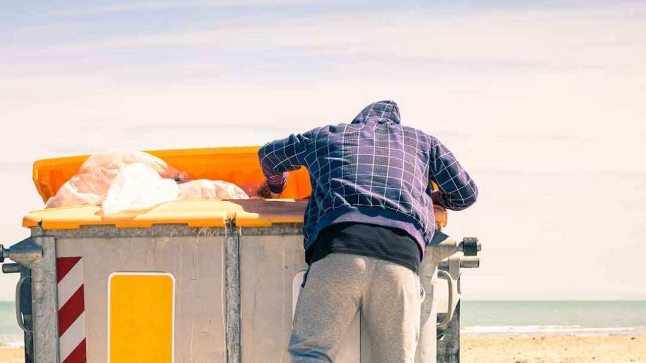 Man digs through rubbish dumpster