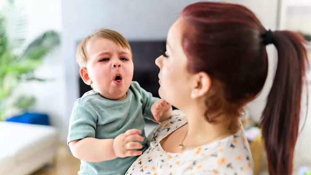 A child coughs in a woman's arms