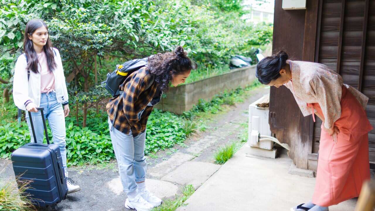 Owner of Japanese inn greeting female tourists from oversees