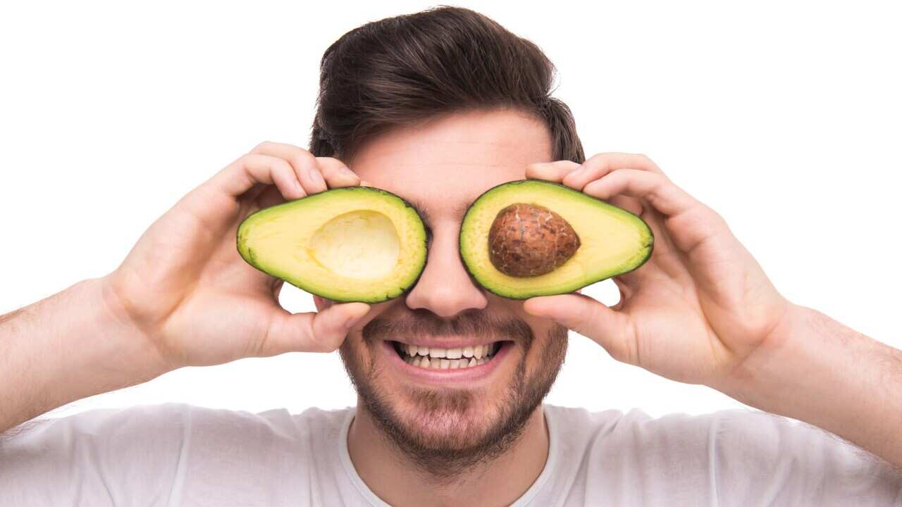 Man covering his eyes with an avocado