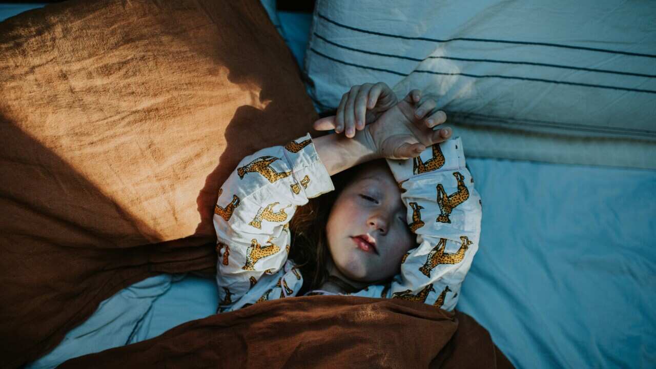 A little girl lies in bed, wrapped in a cozy duvet