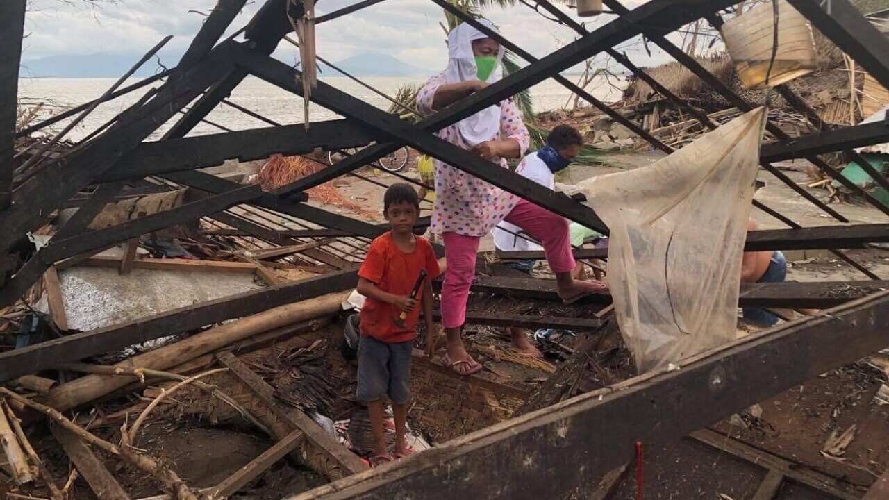 A boy and his grandmother inspect their house damaged by typhoon Rolly in the Philippines