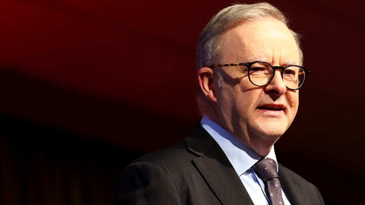 Prime Minister Anthony Albanese in front of a red background.