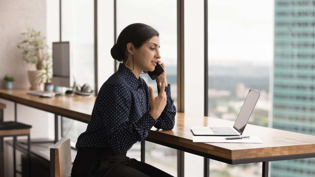 Concentrated young busy Indian businesswoman multitasking in office.