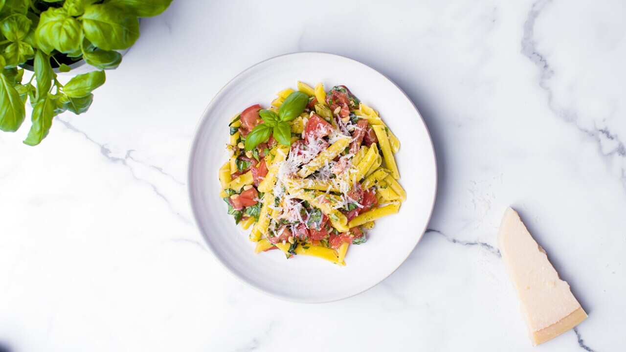 Chopping board tomato and basil pesto pasta