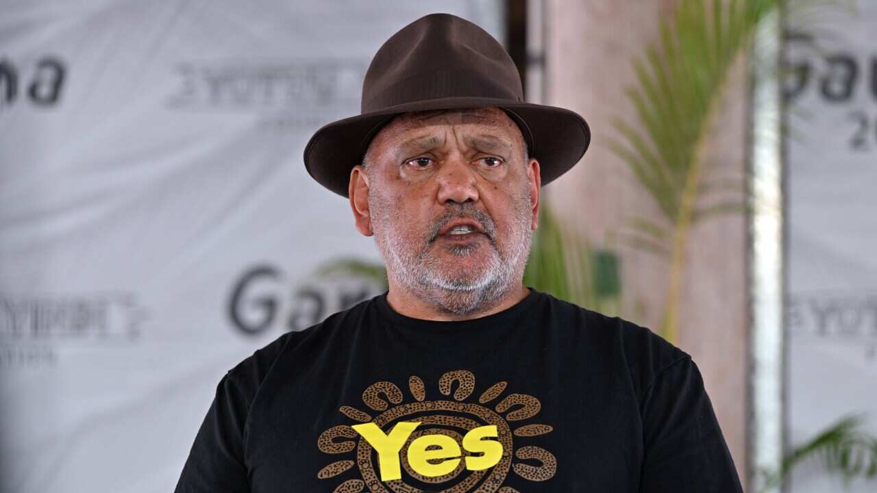 A man wearing a brown hat and t-shirt speaks.