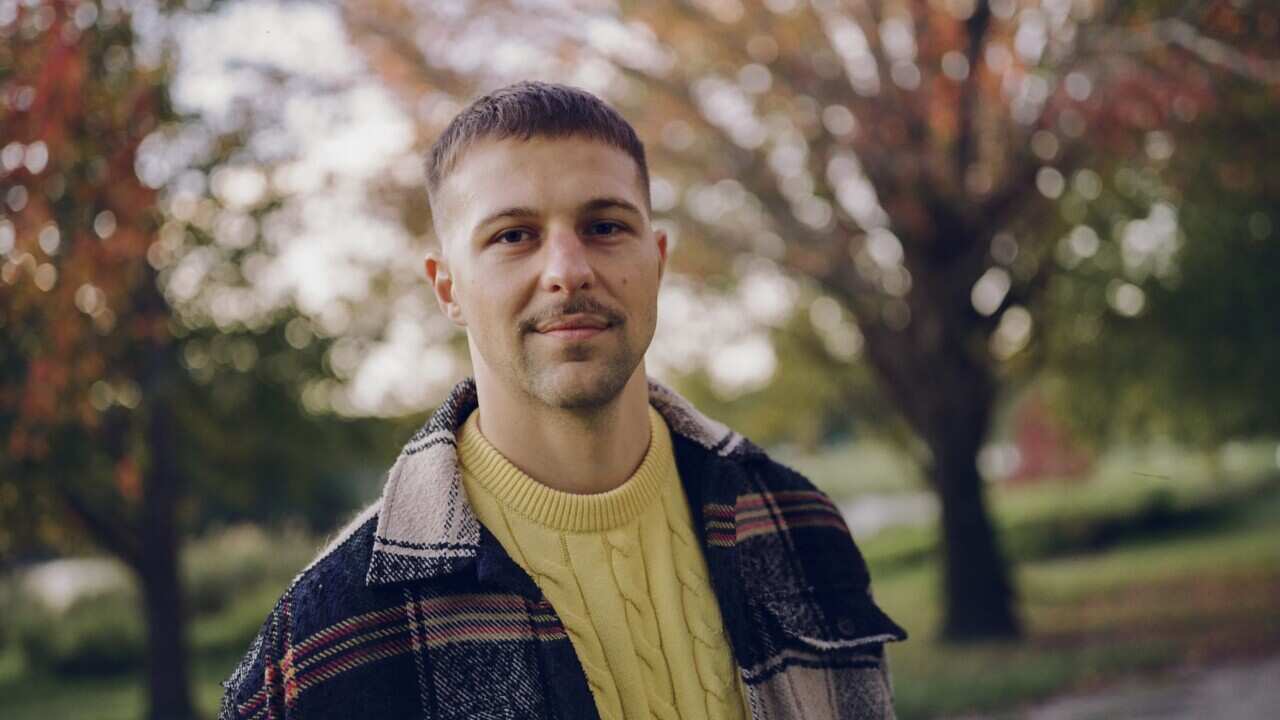 A man in a yellow jumper and plaid jacket 