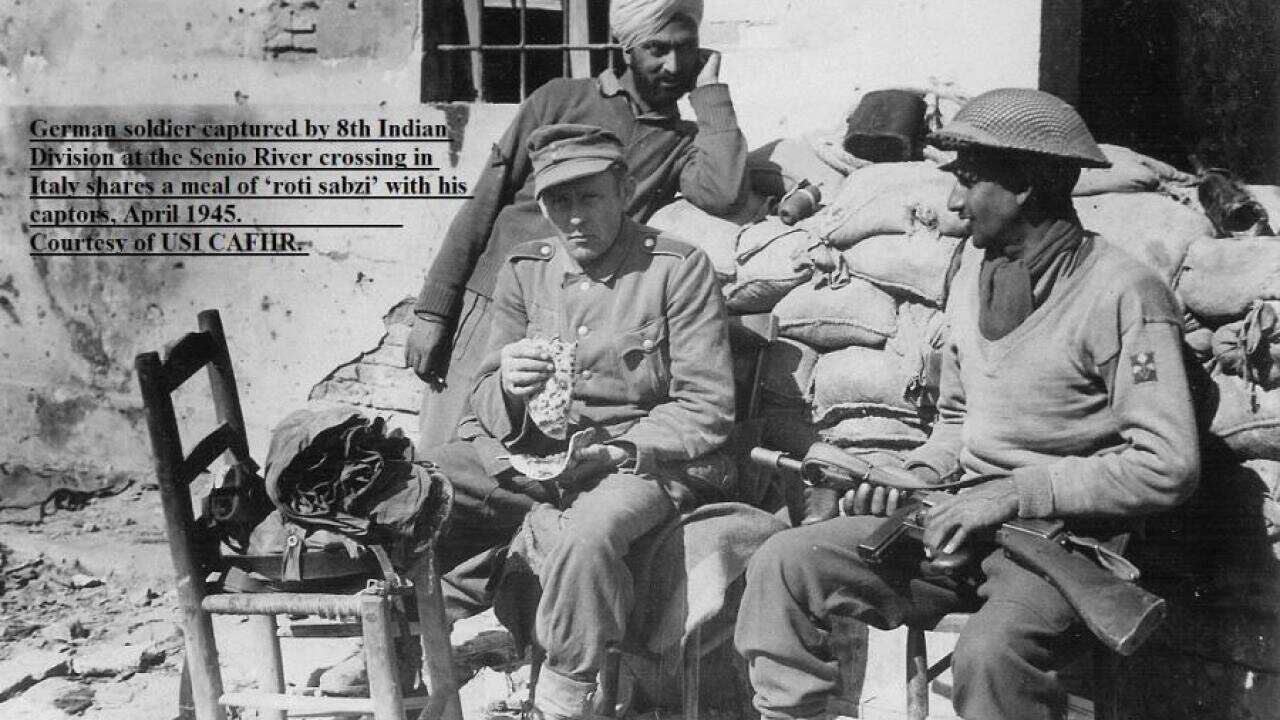 German soldier captured by 8th Indian Division at the Senio River crossing in Italy shares a meal of ‘roti sabzi’ with his captors, April 1945.