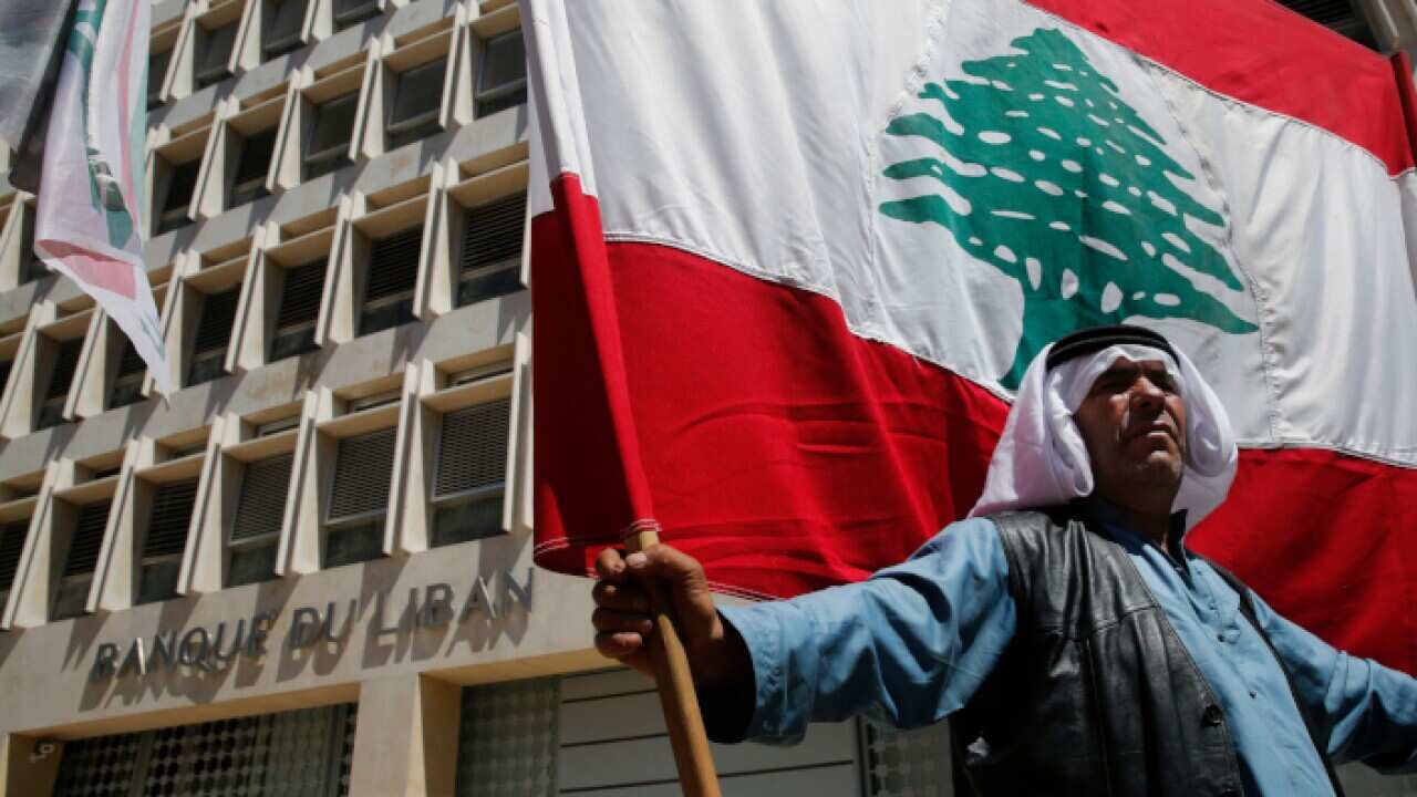 A retired Lebanese soldier holds a national flag, during a protest in front the central bank headquarters, in Beirut, Lebanon