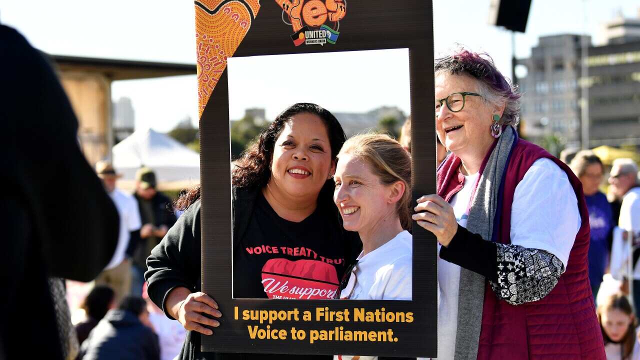 Three people hold a placard.