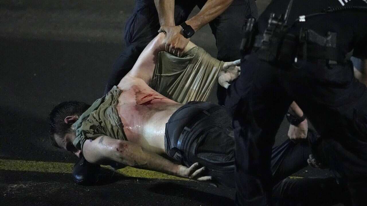 An injured man is dragged away by two policemen.