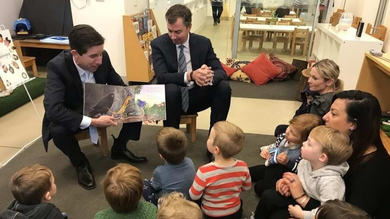 Federal education minister Simon Birmingham (left) is urging families to sign up to a new childcare scheme.