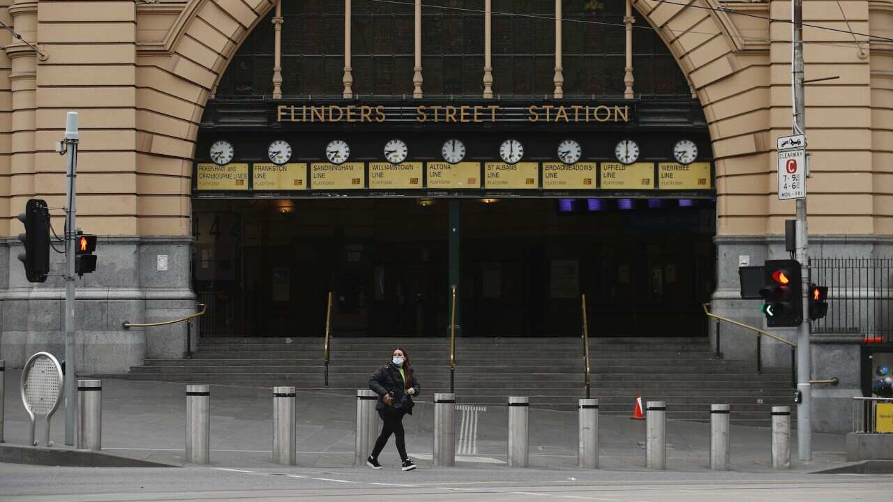 A person is seen crossing a quiet Flinders Street in Melbourne, Monday, July 19, 2021.  (AAP Image/Daniel Pockett) NO ARCHIVING                                  