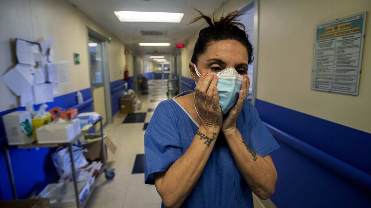 Nurse Cristina Settembrese fixes two masks to her face during her work shift in the COVID-19 ward at the San Paolo hospital in Milan, Italy, April, 2020.