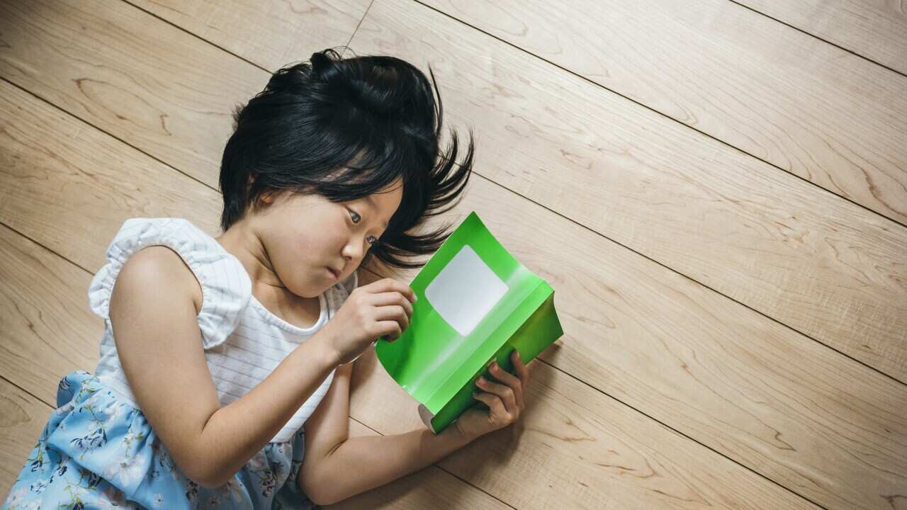 Cute little girl reading book on the floor