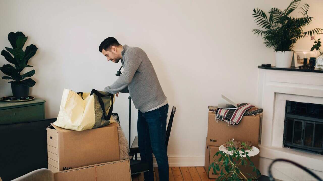 Man searching in bag while standing by wall at living room