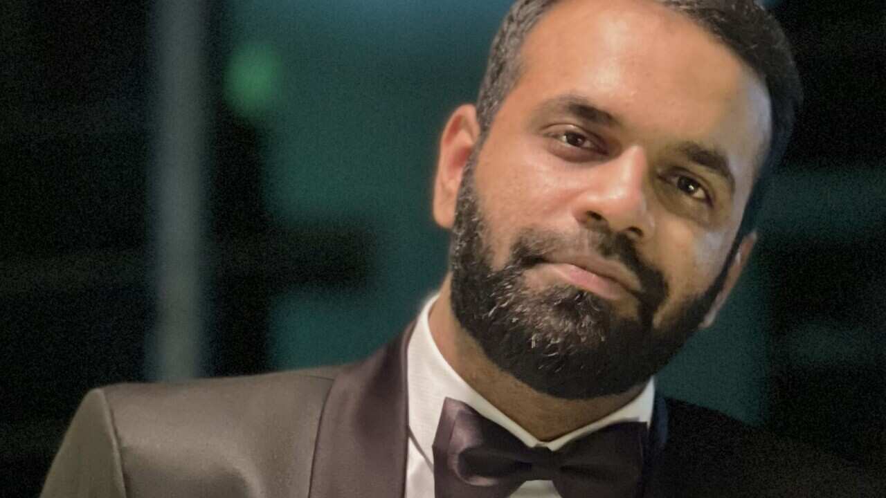 A middle-aged man in a bow tie looks at the camera.