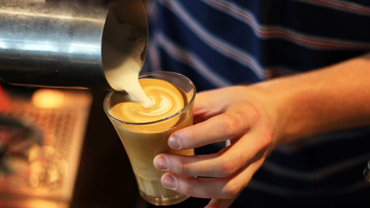 Pouring milk into a glass of coffee