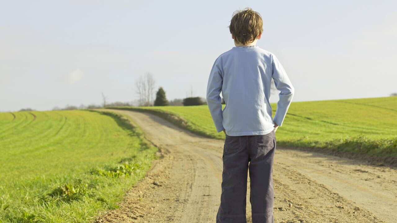 Boy standing, back, sad