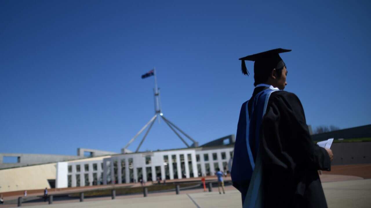 A university graduate is seen outside Parliament House in Canberra.