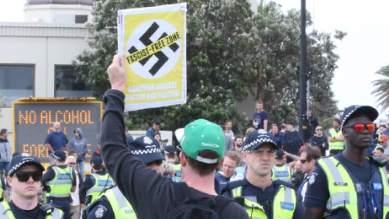 Far-right extremists, escorted by police, protesting and holding up swastika signs.