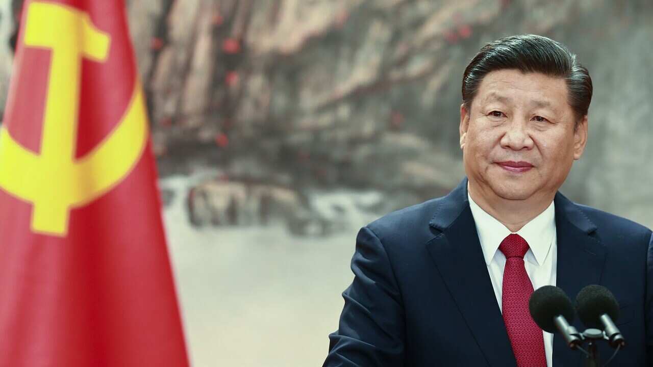 President Xi Jinping stands at a lectern with a flag on his left.