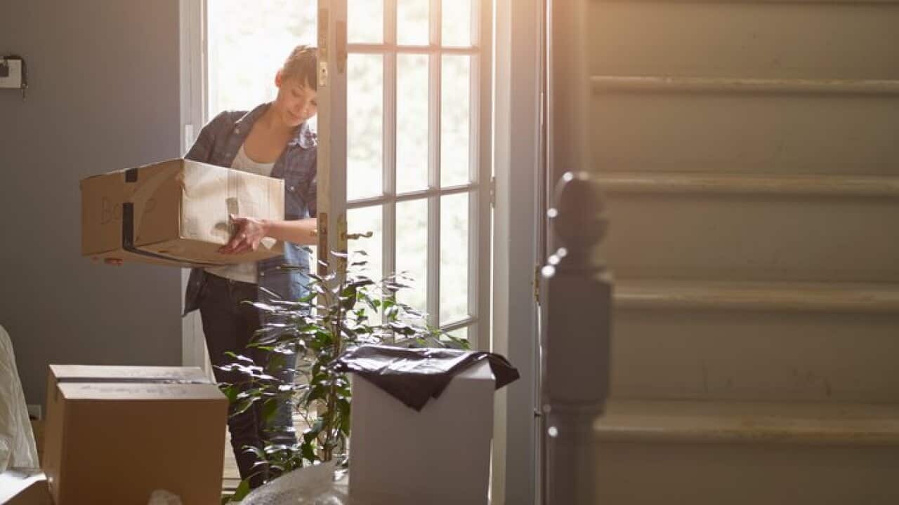 And woman carrying a packing box into her new home