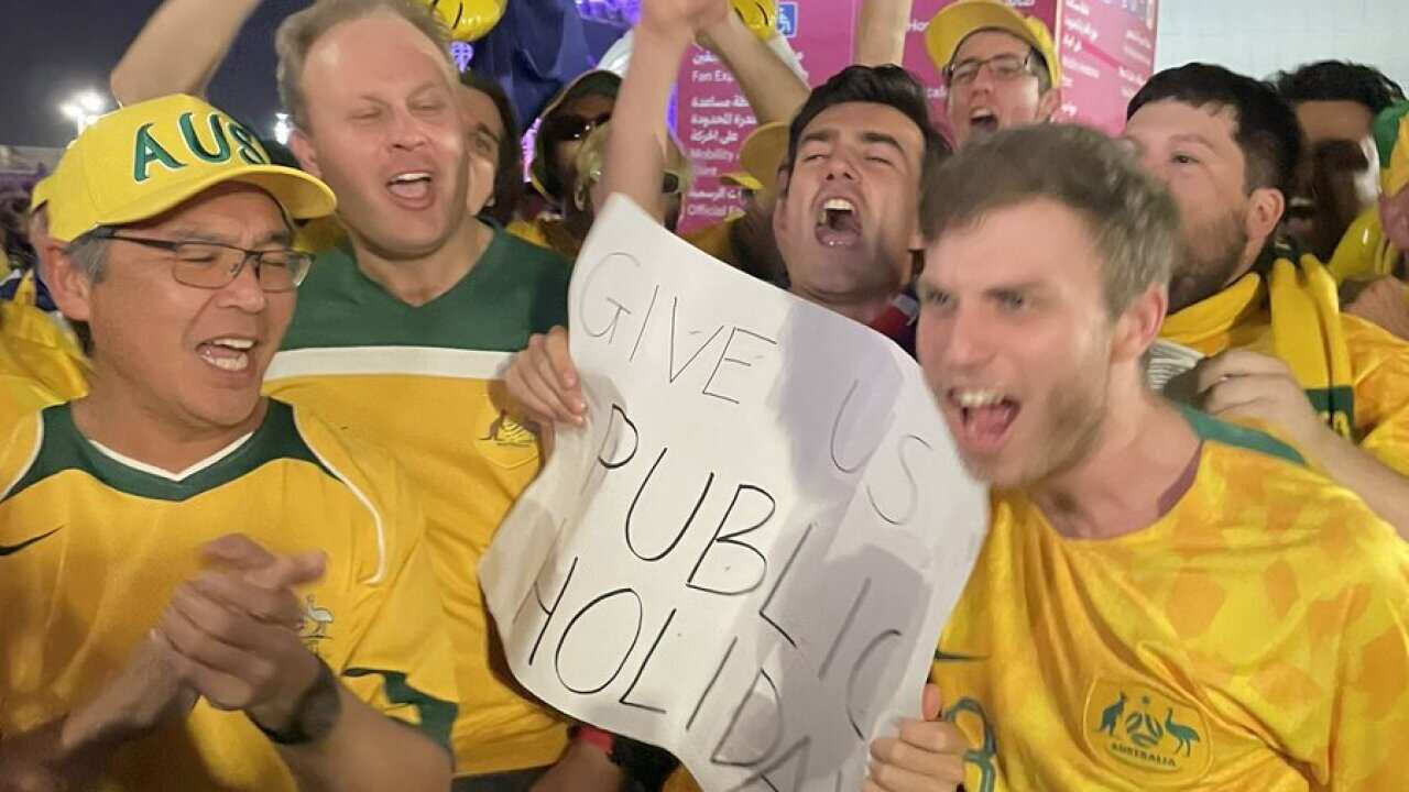 Socceroos fans celebrating and holding a sign that reads: "GIVE US PUBLIC HOLIDAY".