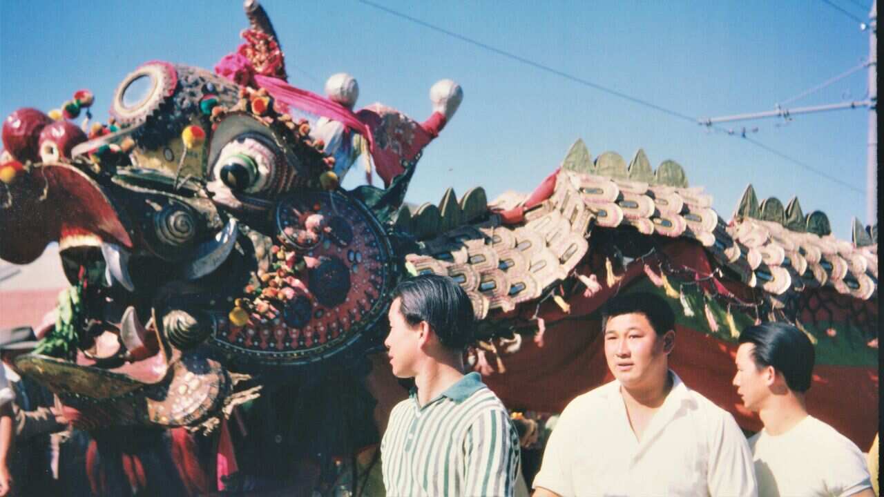 Three Northeastern Asian men stand beside a Chinese dragon 