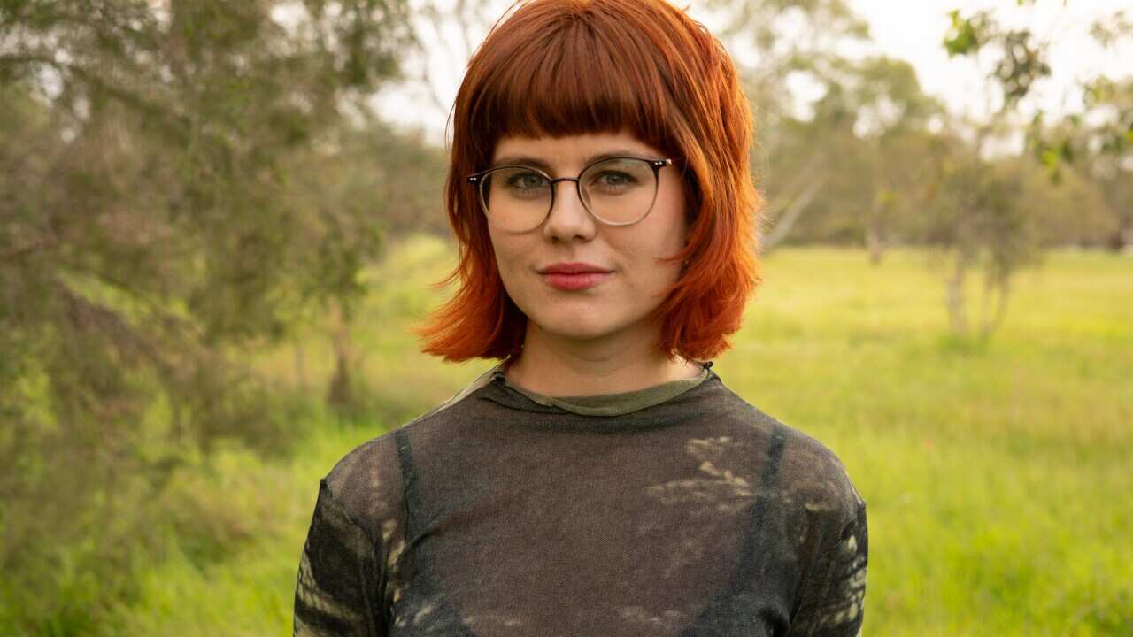 A woman stands for a photo outdoors. 