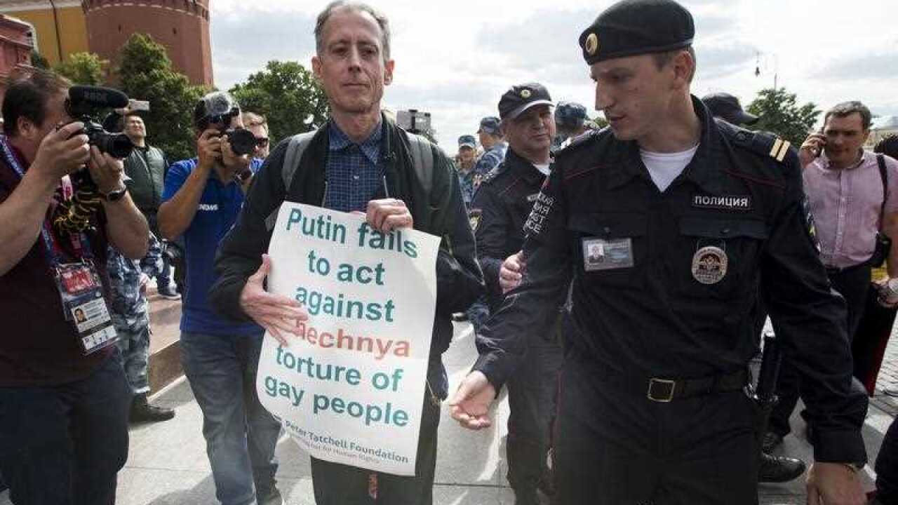 Russian police detain gay rights activist Peter Tatchell, as he holds a banner that read "Putin fails to act against Chechnya torture of gay people".