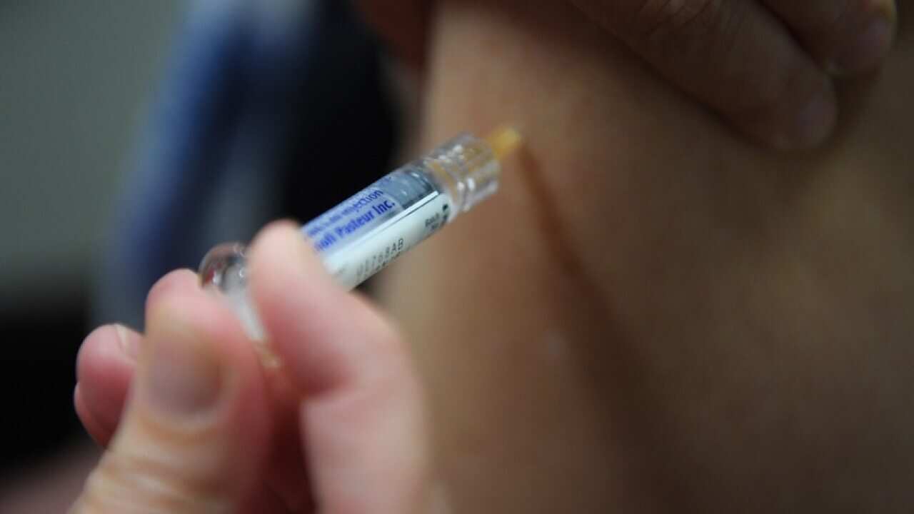 Image of a person being injected by a syringe on an arm.