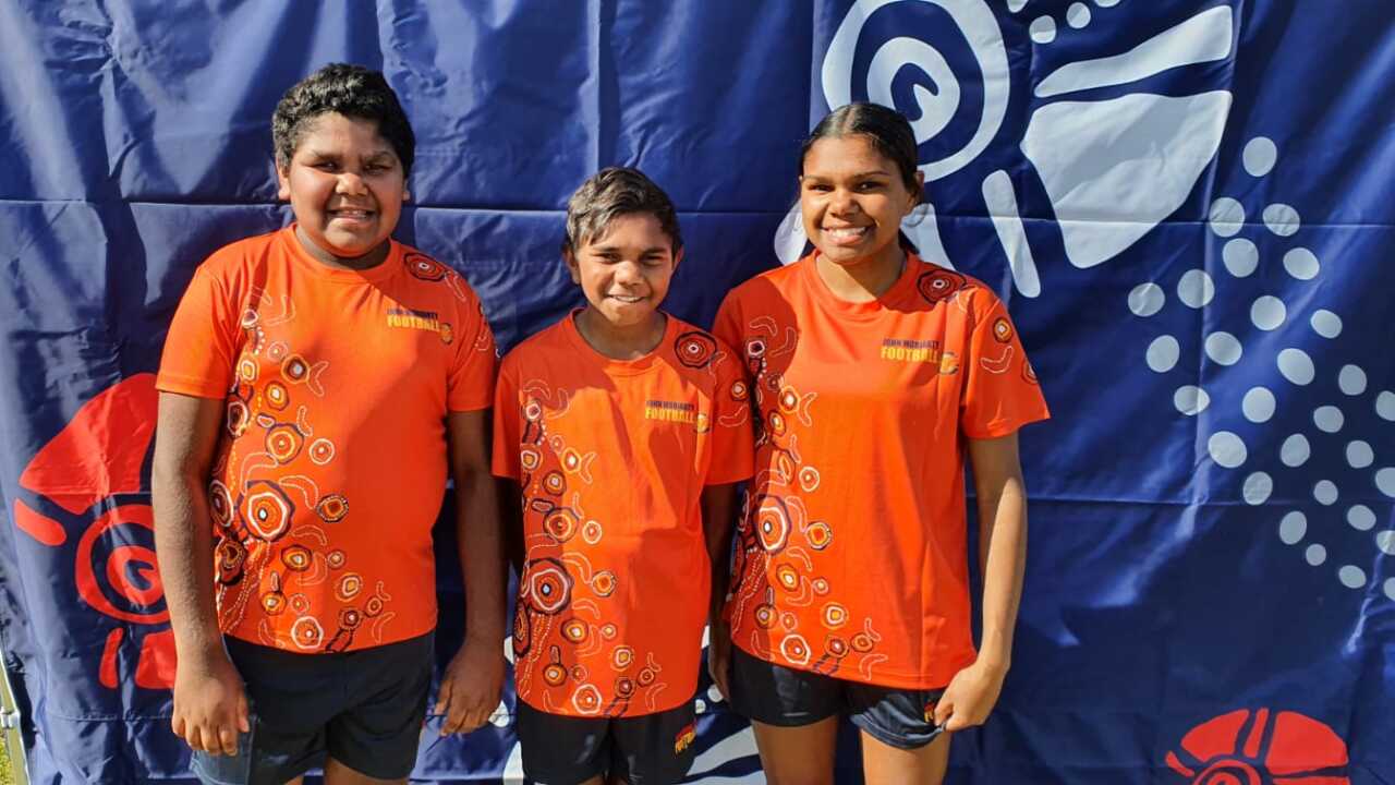 Three kids in soccer uniforms with Indigenous designs on them