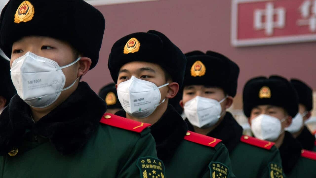 Chinese police officers wearing masks stand in front of the Tiananmen Gate in Beijing.