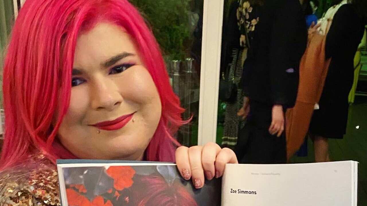 A woman in a wheelchair holding up a magazine she is featured in.