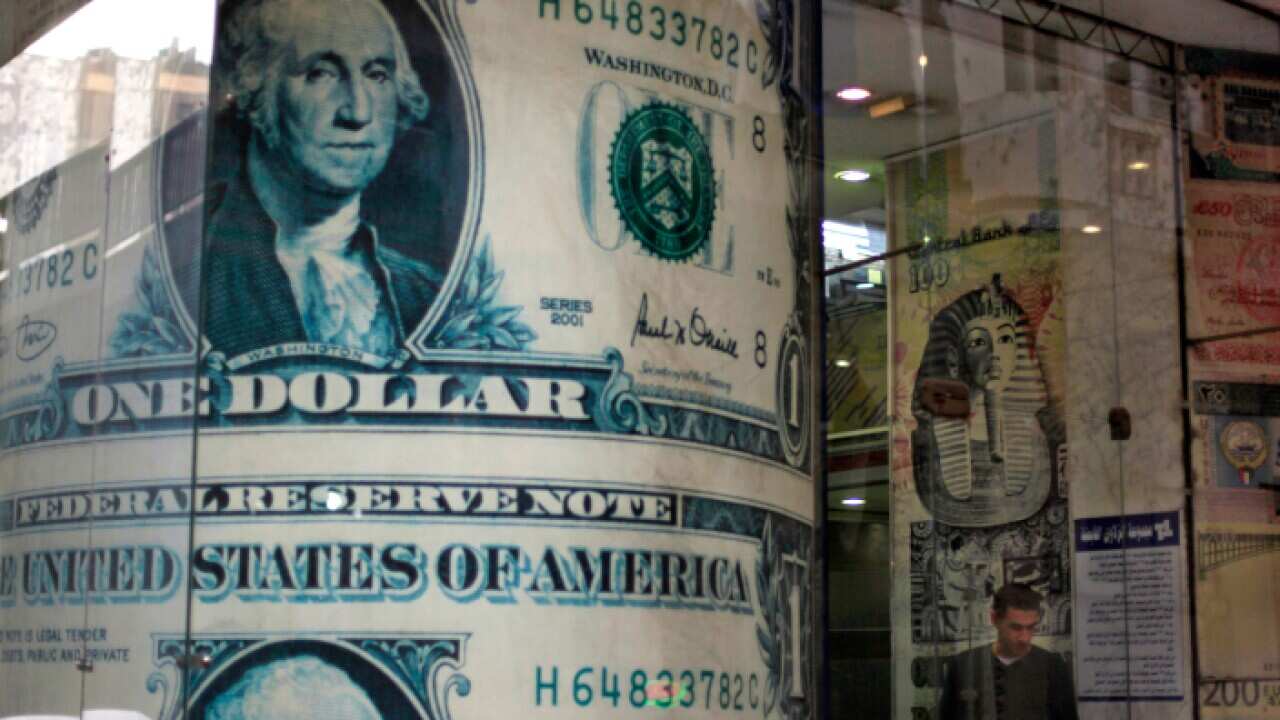 An Egyptian man stands next to a giant poster of U.S. dollars inside a currency exchange office in Cairo