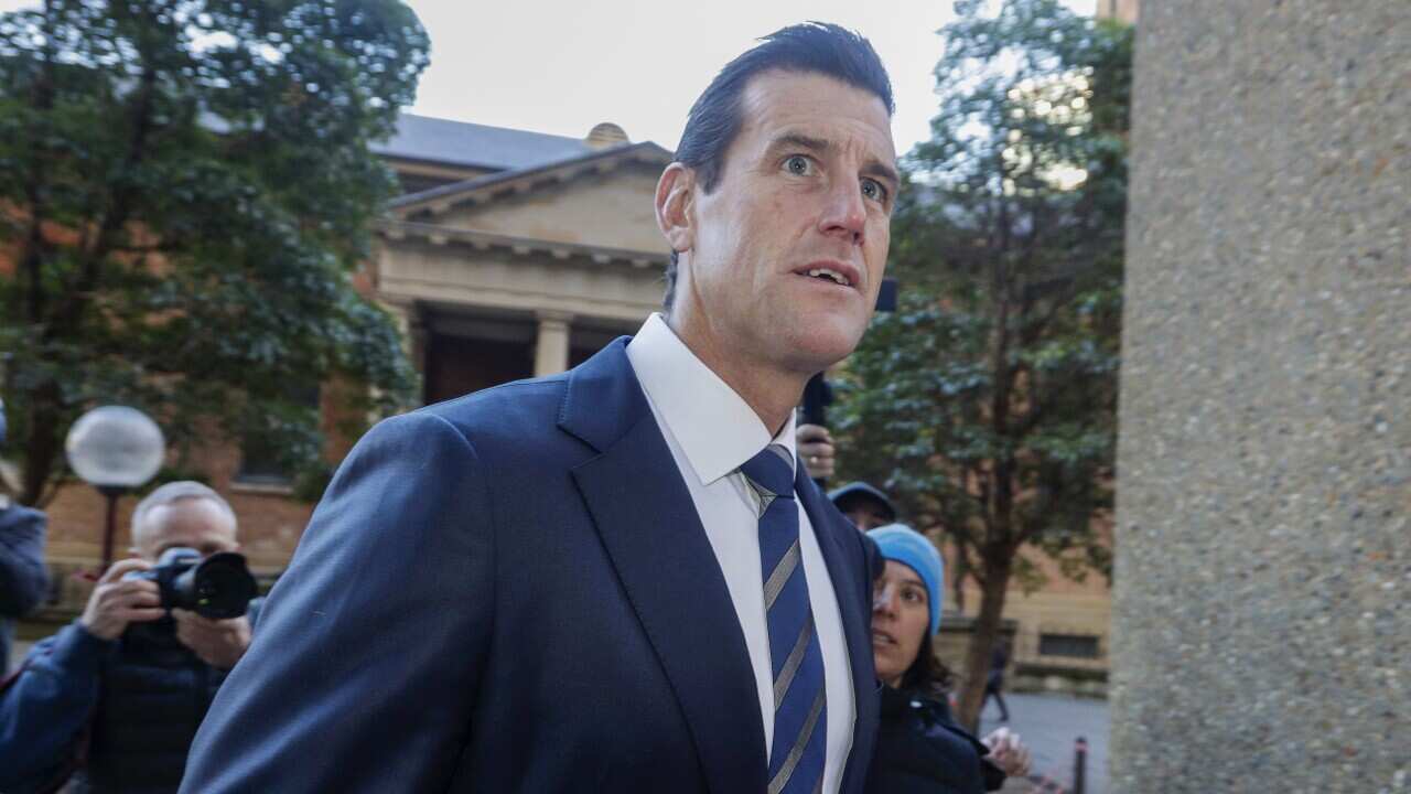 A man in a blue suit and a tie enters a court building.