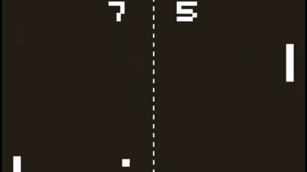 A screenshot of the video game pong with a dotted line down the middle, a bar on each side of the screen, a small dot to one side of the middle line and both player's scores at the top.